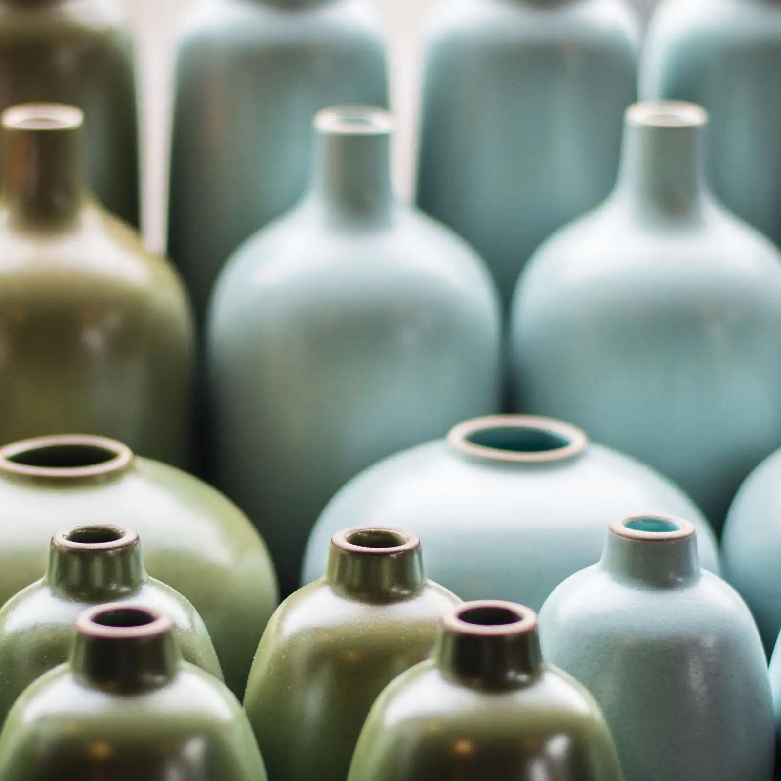 Rows of green and blue-grey glazed bottle vases in different sizes