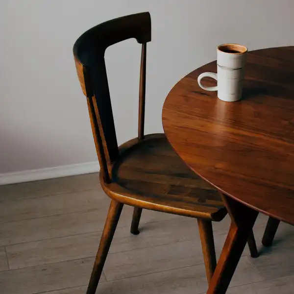 A dark wooden dining chair beside a round walnut table