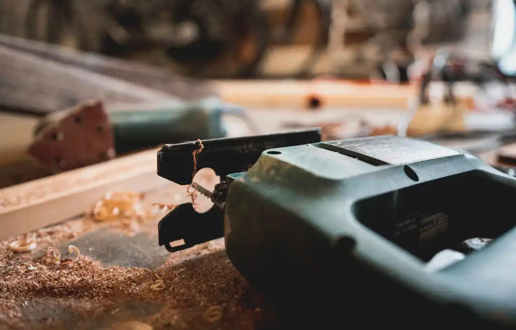 A jigsaw resting on a board among sawdust and offcuts