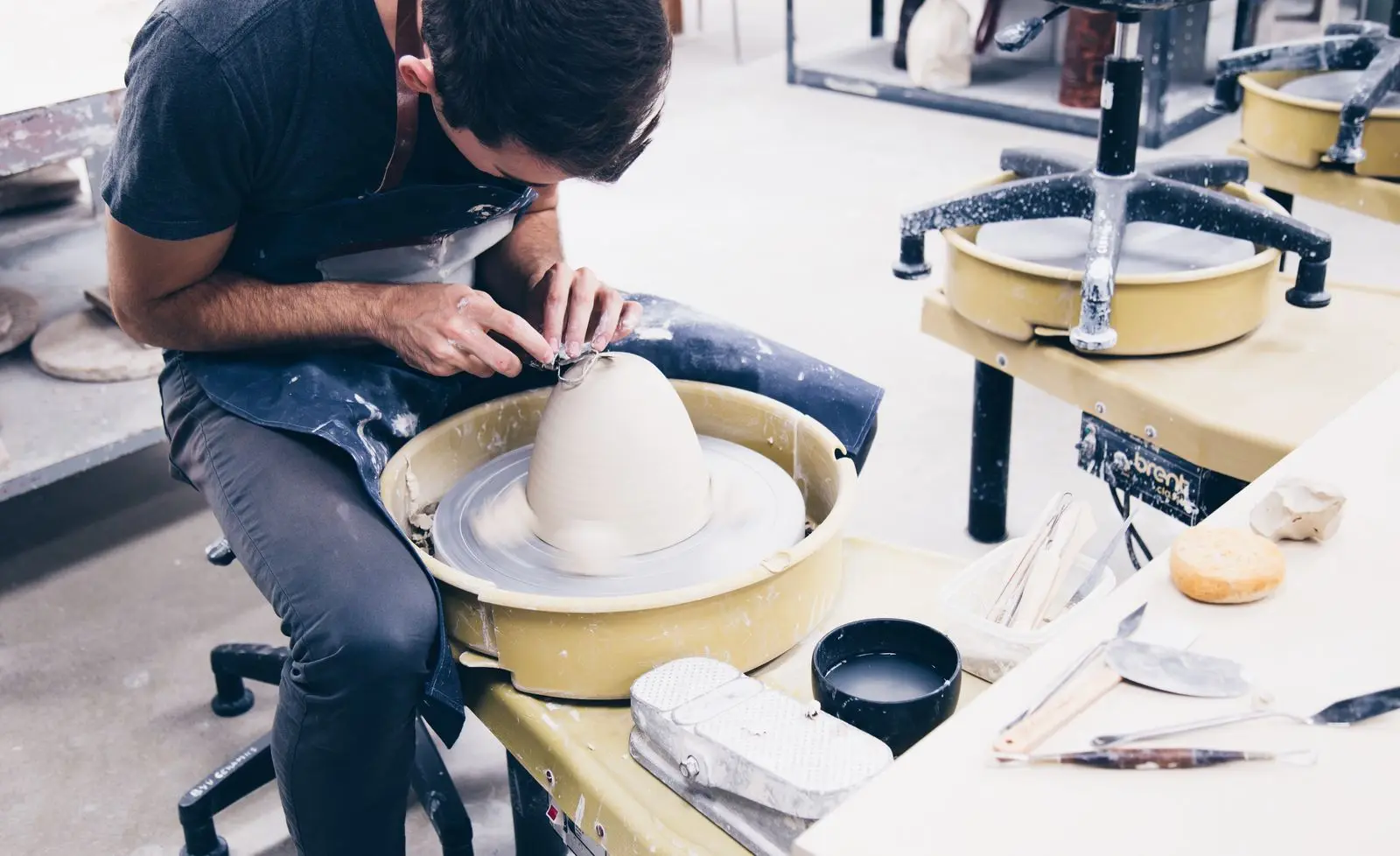 A potter at the wheel pulling up a tall white form